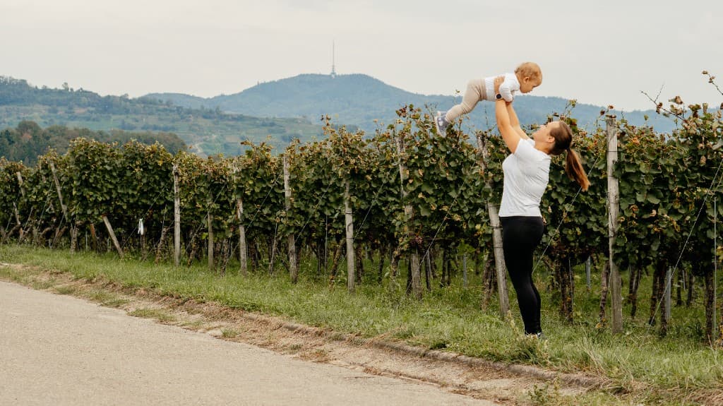 Miriam von Kaiserstuhl-Fit hebt ihr Kind in den Reben am Kaiserstuhl in die Höhe